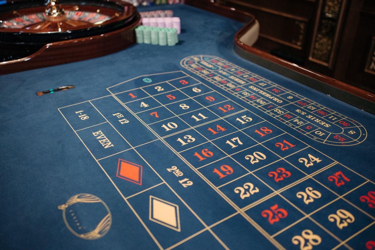 Side view of a navy roulette table, wooden wheel and quiet chip stacks