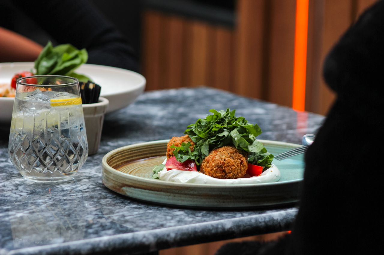 Gourmetrett og krystallglass på mørk stein i herregårdens restaurant