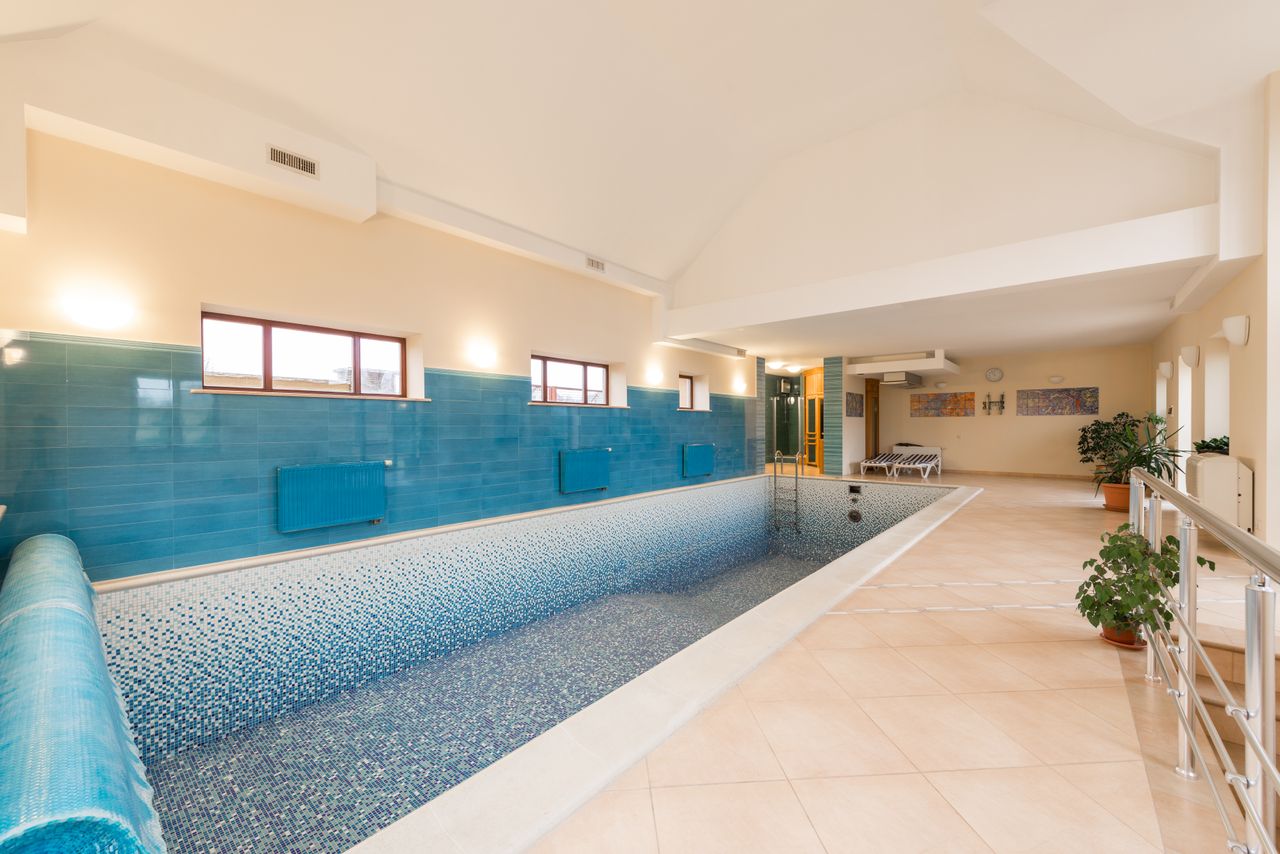 Indoor swimming pool with mosaic tiles and lounge seating